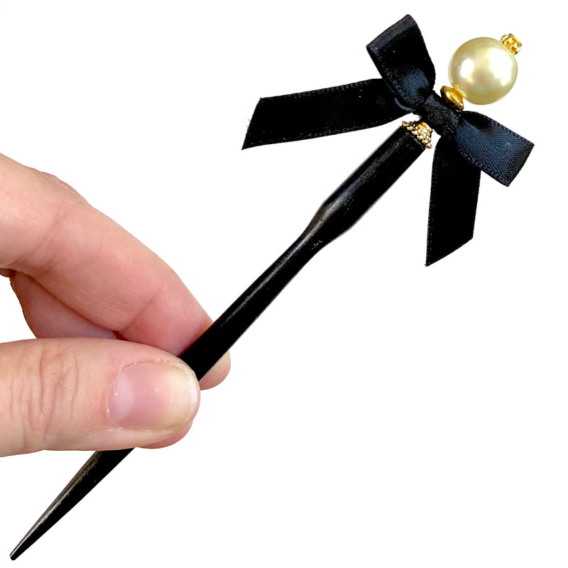Our gold version of the Audrey hair stick is made with an ivory glass pearl and black satin bow. 