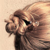 A blonde woman wearing the Abigail Hair Stick in her messy updo.
