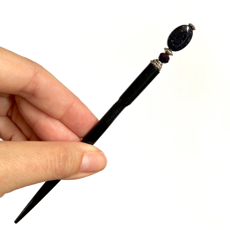 A close up of the Andromeda Tidal Hair Stick made from blue goldstone.