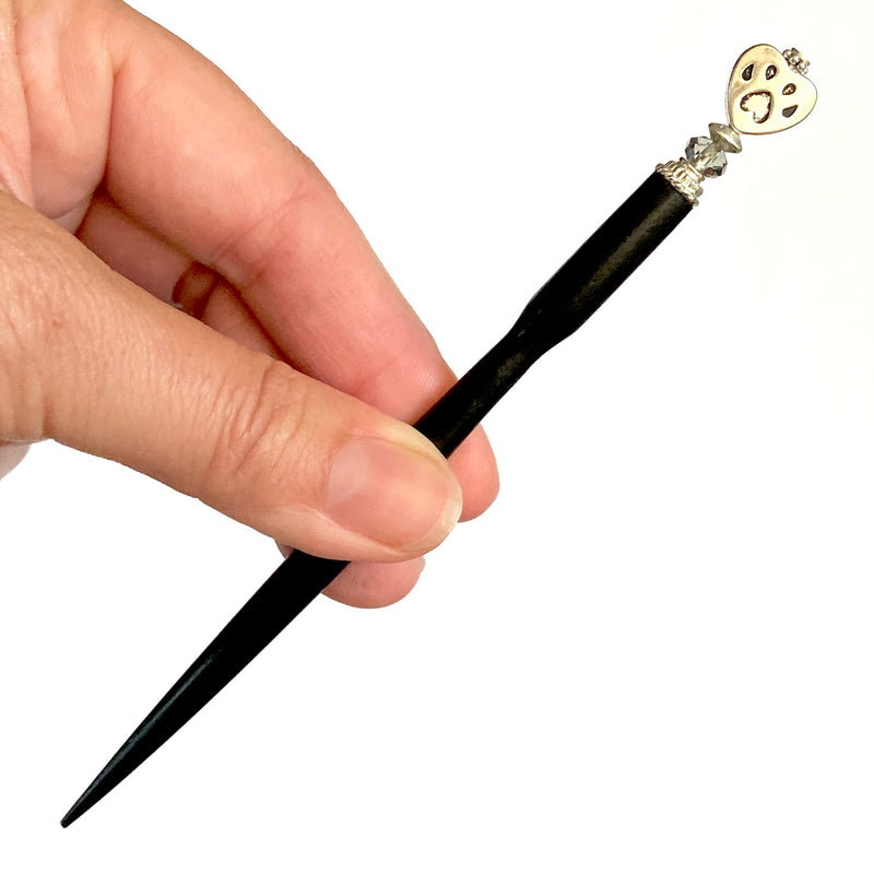 A close up of our Bailey Hair Stick made with a heart-shaped dog paw print metal bead and Swarovski crystal.