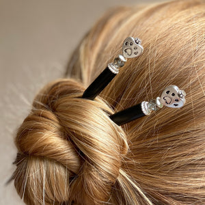 A woman wearing two of our Bailey Hair Sticks made with a heart-shaped dog paw print metal bead and Swarovski crystal.