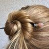 A woman wearing one of our Farah Hair Sticks made from peach moonstone. 