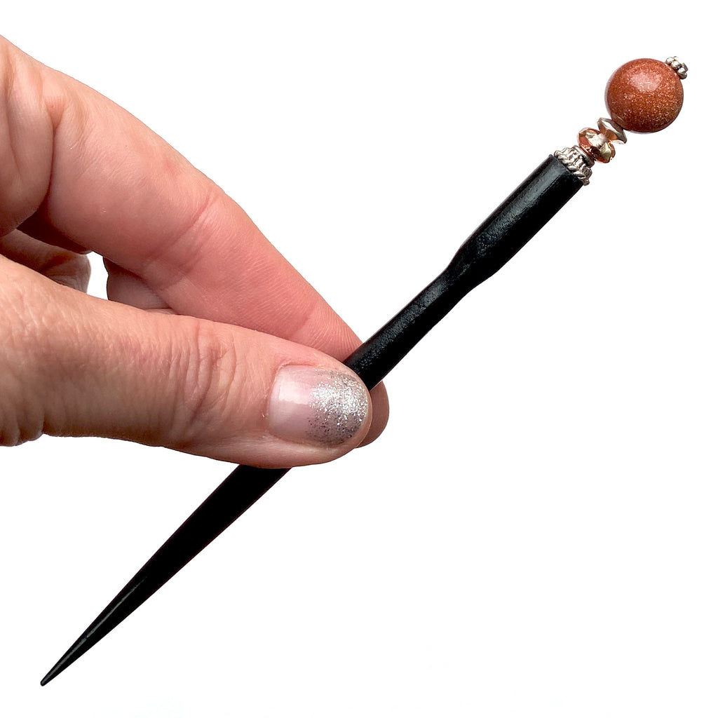 A full shot of our standard size Kennedy Hair Stick made from copper-colored goldstone.
