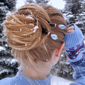 A blonde woman wears two Tidal Hair Sticks in the snow