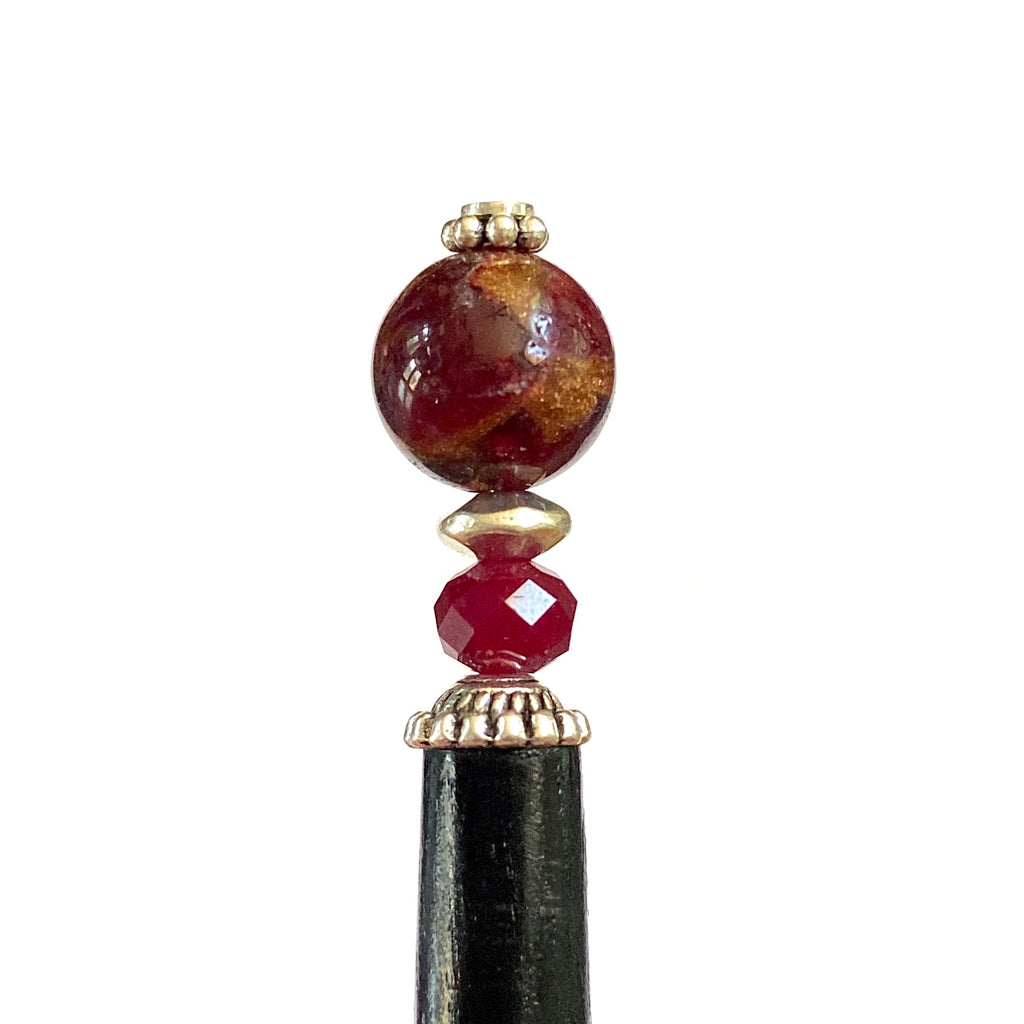 A close up of the Wynn Tidal Hair Stick made from red magenta pyrite quartz