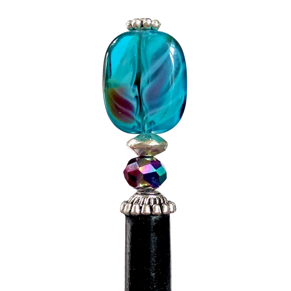 A close up view of the Zara Hair Stick made from teal blue and red swirl Czech glass beads