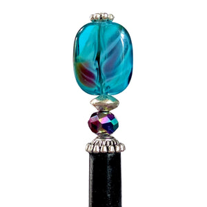 A close up view of the Zara Hair Stick made from teal blue and red swirl Czech glass beads