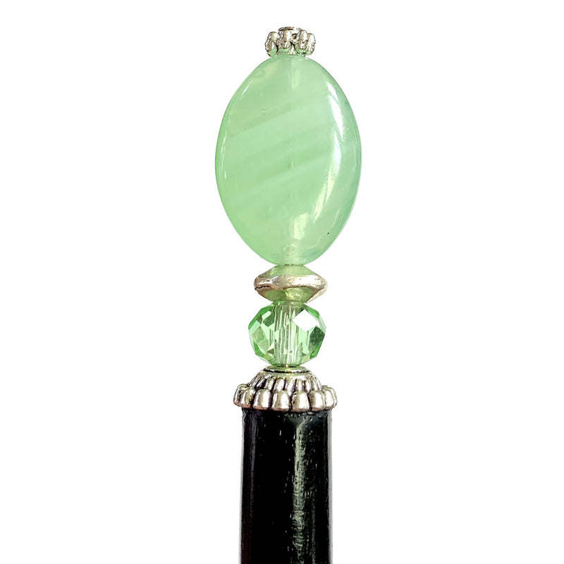 A close up of our Remy hair sticks made from oval green swirl Czech glass beads. 