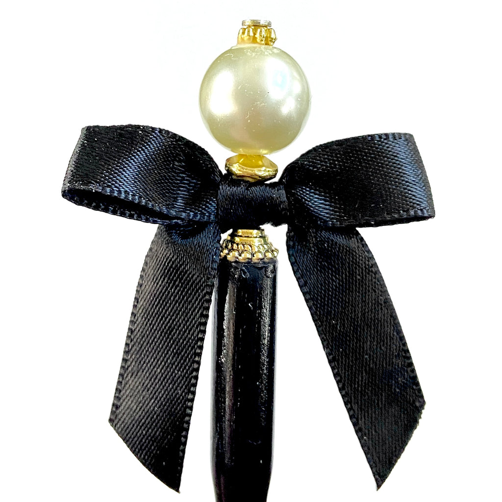 Our gold version of the Audrey hair stick is made with an ivory glass pearl and black satin bow. 