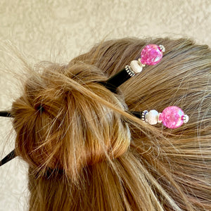 A woman wears two of our Chelsea Hair Stick made with hot pink crackle glass beads