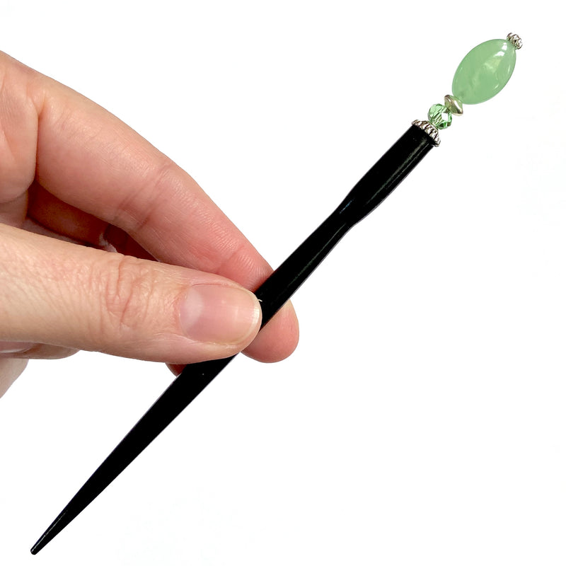 A close up of our Remy hair sticks made from oval green swirl Czech glass beads. 