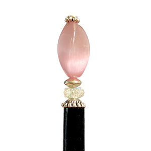 A close up of the Roxy Tidal Hair Stick made of pink cat's eye glass
