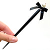 A full shot of the large size of the Audrey Hair Stick made with ivory glass pearl beads and a classic black satin bow.