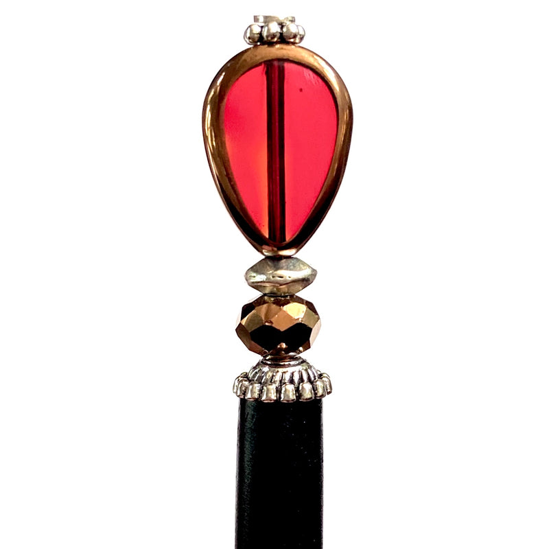 A close up of our Reina Hair Stick made from a red Czech glass bead with bronze edging