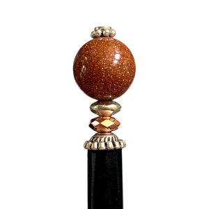 A close up of our Kennedy Hair Stick made from copper-colored goldstone