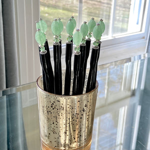 A group of our handmade Remy hair sticks made from oval green swirl Czech glass beads. 