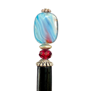 A close up of the Charlotte Tidal Hair Stick made from red white and blue swirl glass beads.
