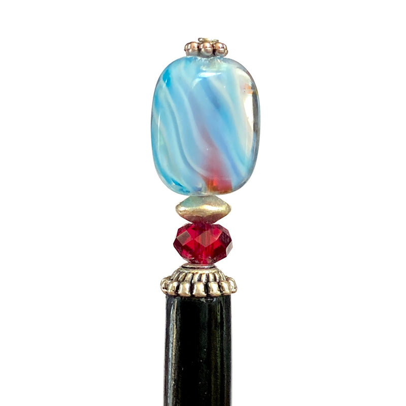 A close up of the Charlotte Tidal Hair Stick made from red white and blue swirl glass beads.