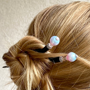A woman wears a set of our Olivia Hair Sticks made from pastel pink and blue acrylic bubblegum beads.
