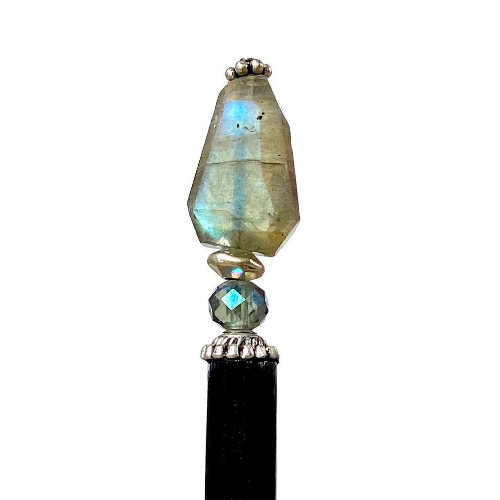A close up of a Dylan Tidal Hair Stick made from faceted labradorite nugget stone.
