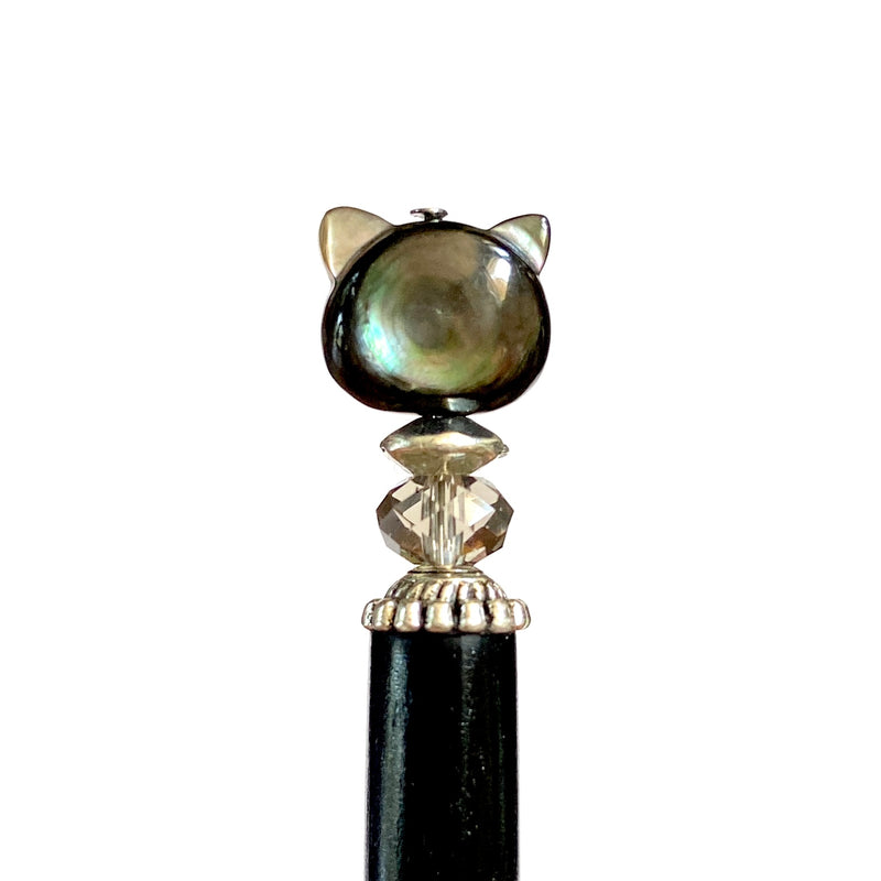 A close up of our Kat Hair Stick made from a black mother of pearl bead shaped like a cat head.