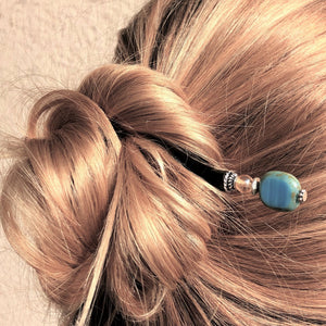 A blonde woman wearing the Adelaide Tidal Hair Stick to secure her messy hairbun.