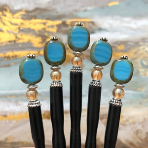 Five Adelaide Tidal Hair Sticks with a gold and blue background.