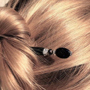 A blonde woman wearing the Andromeda Tidal Hair Stick made from blue goldstone.