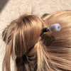 A blonde woman wears her hair in a bun using the Bella Tidal Hair Stick made from blue lace agate stone.