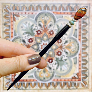 A hand holding the Bree Tidal Hair Stick made from a teardrop Jasper bead.