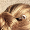 A woman wearling a hair bun secured with the Cali Tidal Hair Stick made from a natural shell bead and pearl accent bead