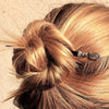 A blonde woman wears a hair bun using the Cassie Hair Stick made from lavender gray agate stone nuggets.