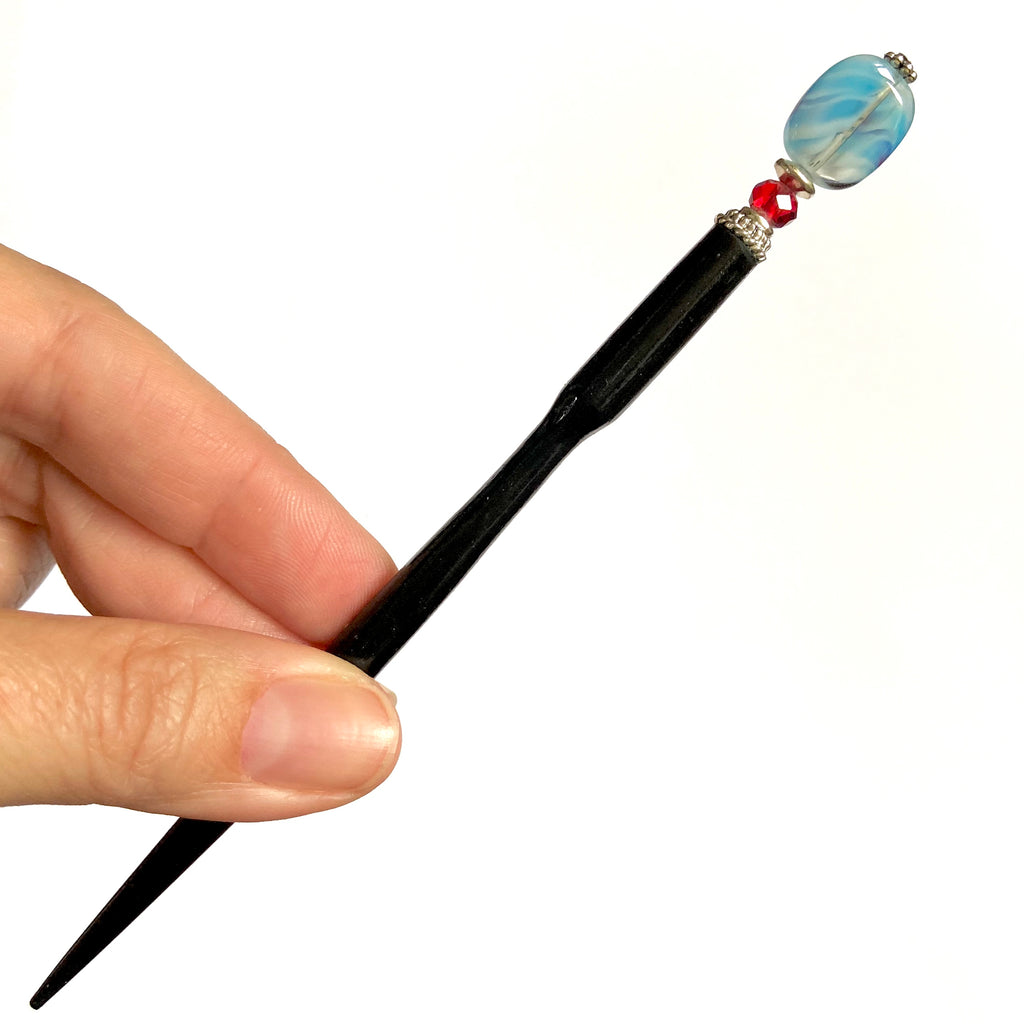 A full shot of the Charlotte Tidal Hair Stick made from red white and blue swirl glass beads