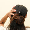 A brunette woman wears a tanzanite Claudia Tidal Hair Stick in her half-up hairstyle.