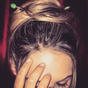 A blonde millennial woman wears a messy bun using two Dakota Hair Sticks.