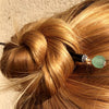 A blonde woman wears a hairbun using the Daliah Hair Stick made from aqua African Recycled Glass beads.