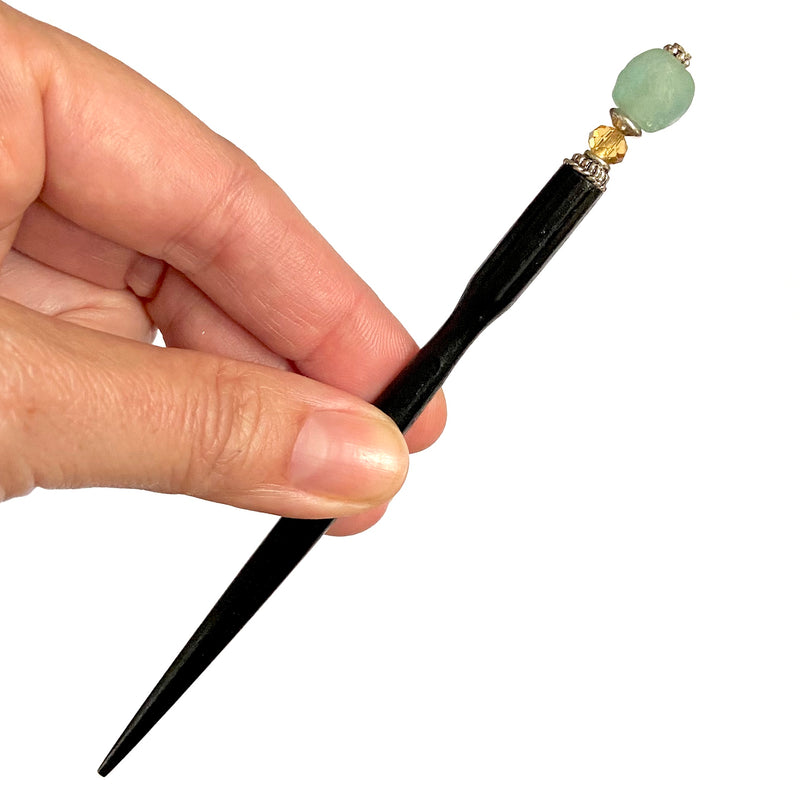 A blonde hair bun is secured by two of the Daliah Hair Stick made from aqua African Recycled Glass beads.