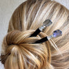 A blonde woman wearing two Labradorite Hair Sticks in her hair bun
