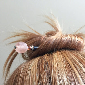 A high messy bun using the Ellen Hair Stick made from blush pink peach African Recycled Glass beads.