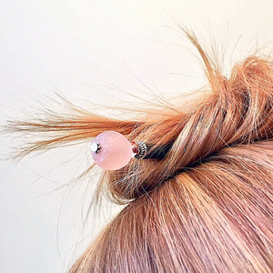 A blonde, high messy bun is secured with the Ellen Hair Stick made from blush pink peach African Recycled Glass beads.