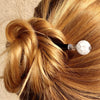 A blonde woman wears a messy bun by using the Elodie Hair Stick made from frosted white crackle quartzite beads.
