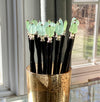 A group of just-made aqua and green Erin Tidal Hair Sticks are drying by a window.