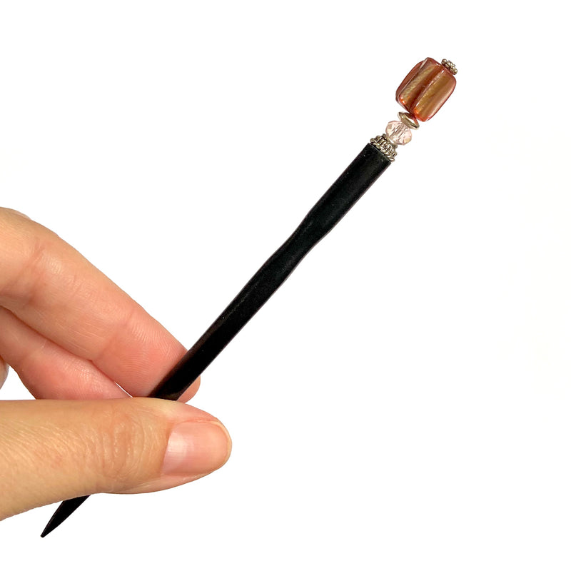 A close up of the Eve Tidal Hair Stick made from pink mother of pearl shell beads