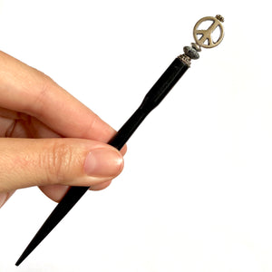 A full shot of the Freedom Tidal Hair Stick made from a silver peace sign and denim-colored accent bead.