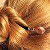 A blonde woman wearing a messy bun using the Gemma Tidal Hair Stick made from Bamboo Agate Stone beads.