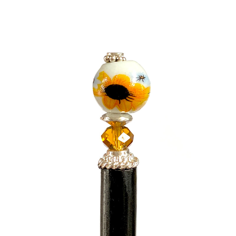 A close up of our Helia Hair stick made from a sunflower ceramic bead