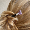 A woman wears one of our purple Iris Hair Stick made from crystal