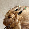 A woman wearing two of the Kathleen Hair Sticks made from gold Czech glass beads
