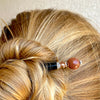A blonde woman wears a Kennedy hair stick made from goldstone