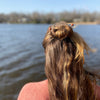 A bronde woman wearing two of our of our Kennedy Hair Stick made from copper-colored goldstone.